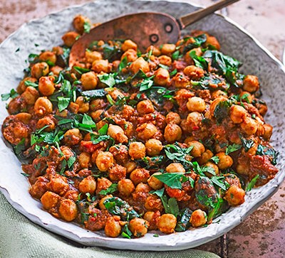 Chickpea curry in white bowl on pink table