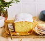 Iced lemon cake on a wire rack next to a knife