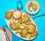 A platter of spring onion and sweetcorn fritters with lemon wedges and soured cream