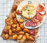 Baked cheese with roasted garlic Jersey Royals served on a platter