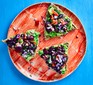 Avocado and black bean triangles topped with onion and tomato on plate