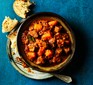 Beef and pumpkin stew in a bowl next to crusty bread