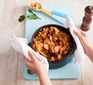 Bigos (Polish stew) in a black casserole pot, held by two hands