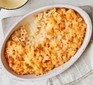 Oval baking dish of macaroni cheese with a spoonful taken out