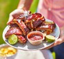 Fall-off-the-bone sticky barbecue ribs served on a platter with lime wedges