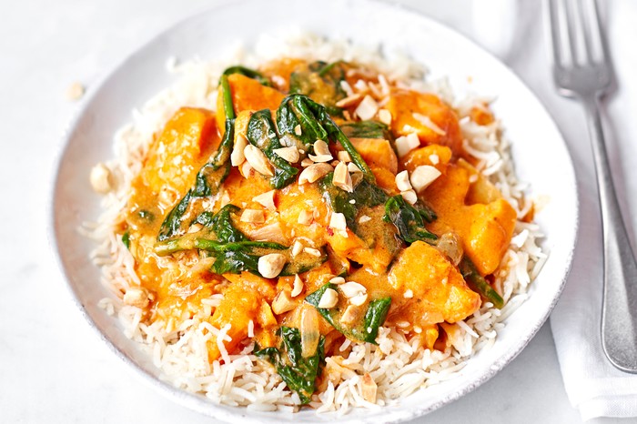 Sweet potato and peanut curry on a white plate with a fork on the side