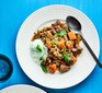 Lamb curry with cucumber raita on plate with spoon