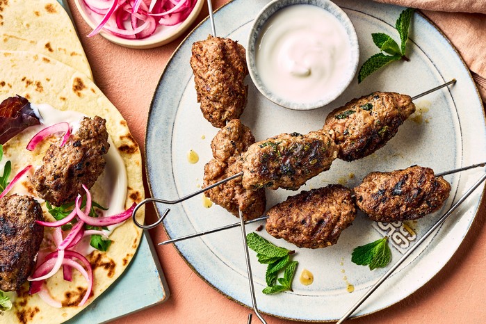 Lamb koftas on skewers served on a plate with a creamy dip