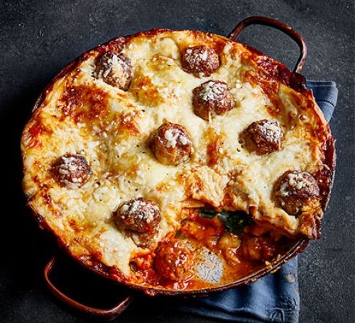 Meatball lasagne topped with melted cheese with a slice cut out