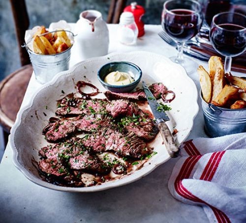 Onglet steak on plate next to pots of potato chips