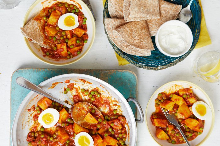 Three bowls of pea, potato and egg curry with rotis