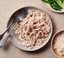 Plate of shredded chicken next to a bowl of rice and plate of pak choi