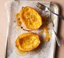 Halved spaghetti squash on a baking tray next to two forks