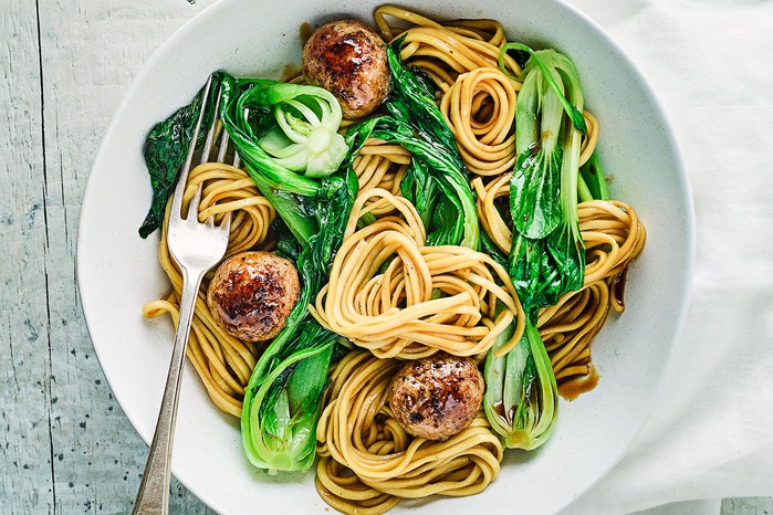 Teriyaki pork meatballs served on a bed of noodles with pak choi