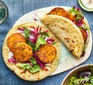 Two vegan kebabs on a serving platter with a bowl of salad on the side