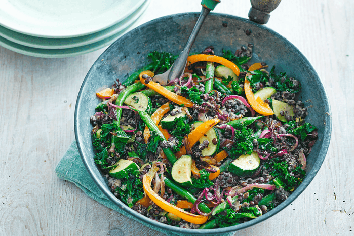 Noodles in a wok with veggies and lentils